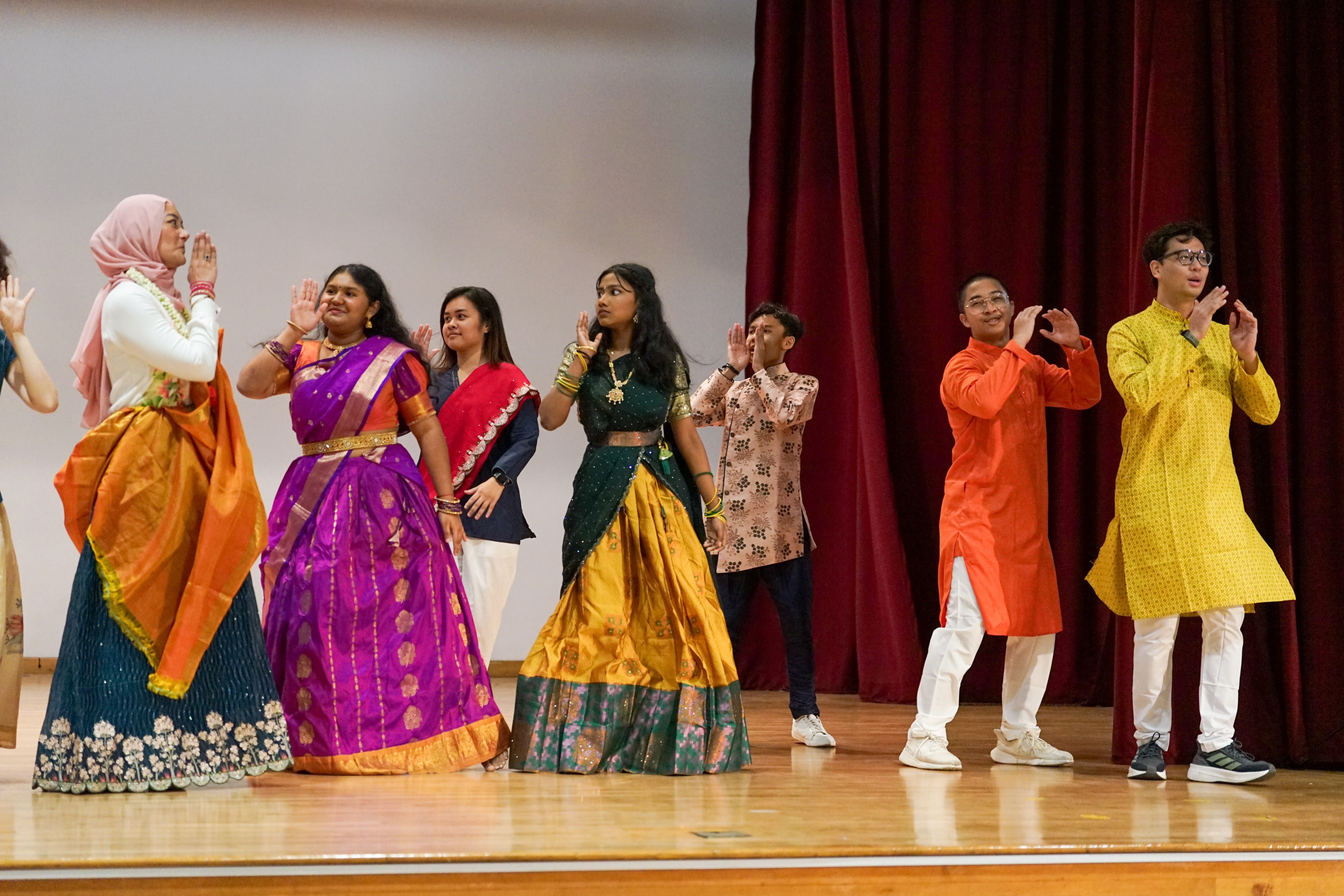 Photo of our VP, Ms Latifah and tamil students wearing their traditional costume and dancing on the school stage.